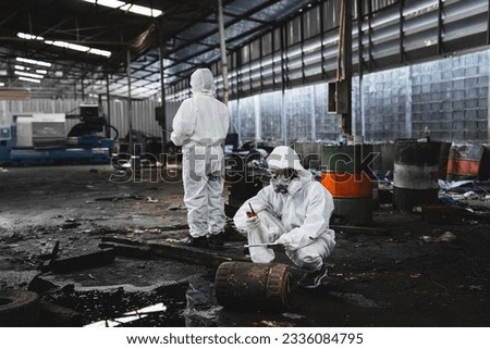 Scientist workers wear protection suit checking chemical contaminated oil in old factory. Protecting Against Hazards and Contamination. Emergency Response to a Radioactive Accident. Royalty-Free Stock Photo #2336084795