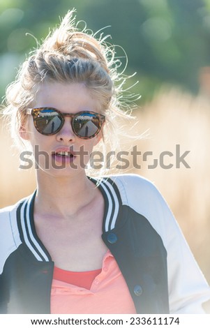 portrait closeup  of a beautiful blond young woman, with a topknot and sunglasses