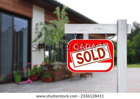 Garage sale sign with Sold sticker near house