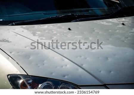 Car hood damaged by major hailstorm hailstones. Car insurance repair dents. Dented car bonnet car after storm weather Royalty-Free Stock Photo #2336154769