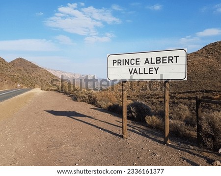 Road sign to Prince Albert Valley with gravel and tar road,  blue sky and mountain ranges in the Karoo