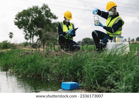 Two Environmental Engineers Inspect Water Quality and Take Water Samples Notes in The Field Near Farmland, Natural Water Sources maybe Contaminated by Toxic Waste or Suspicious Pollution Sites. Royalty-Free Stock Photo #2336173007