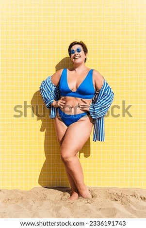 Beautiful and confident plus size woman having fun at the beach, posing on colorful wall background -  concepts about body acceptance, body positive, self confidence and body care