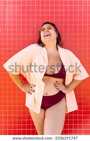 Beautiful and confident plus size woman having fun at the beach, posing on colorful wall background -  concepts about body acceptance, body positive, self confidence and body care