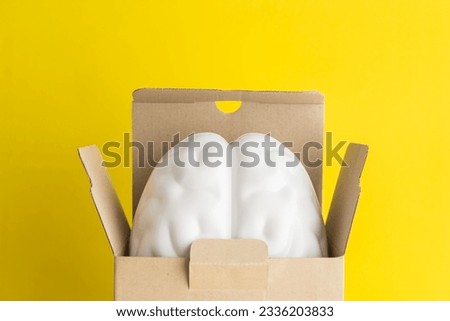 Smart brain is going out of the paper box on yellow background copy space. Concept of think outside the box, creative new idea, innovation technology, think different, startup business.