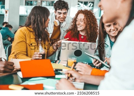 Multiracial university students sitting together at table with books and laptop - Happy young people doing group study in high school library - Life style concept with guys and girls in college campus Royalty-Free Stock Photo #2336208515