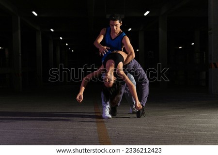 Talented dramatic couple of dancers doing an artistic performance and contemporary dance in a dark parking garage Royalty-Free Stock Photo #2336212423