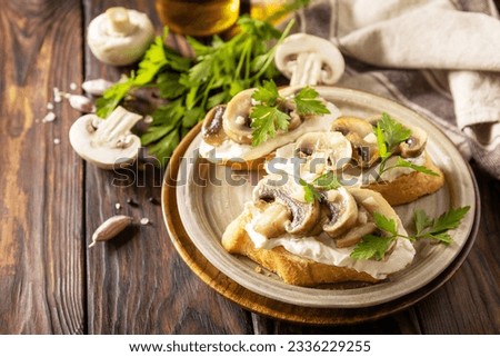 Toasted sandwich from baguettes bread with soft cheese and grilled mushrooms on wooden rustic  table. Homemade bruschetta with mushrooms. Copy space.  Royalty-Free Stock Photo #2336229255