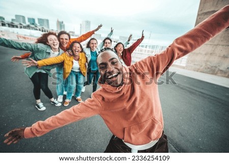 Group of young people laughing together at camera outdoors - Youth community life style concept with guys and girls celebrating and cheering success on city street - Bright filter