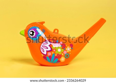 Bird whistle, children's toy isolated on yellow background Entertainment for children