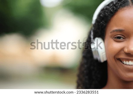 Front view portrait of a face of a happy black woman wearing headphone