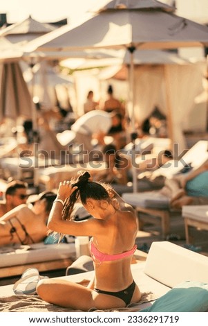 back view of beautiful girl in bikini fixing her hair on the beach