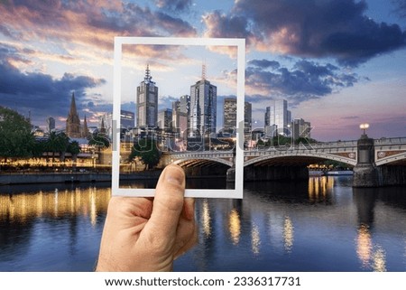 Hand holding an instant photo picture of downtown Melbourne in Australia with actual cityscape in the background
