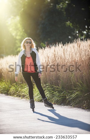 beautiful blond young woman practicing rollerblading in town