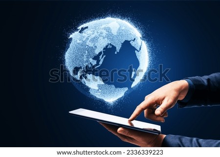 Close up of businessman hand holding and pointing at mobile phone with glowing globe hologram on blurry blue background. Digital earth and metaverse concept