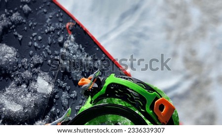 Background photo of a snowboard, boot, and snow from point of view of a ski lift