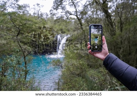 A hand holding a smart phone trying to take a picture of the view.
