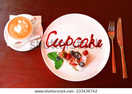 Cup of coffee and tasty cupcake on table in cafe