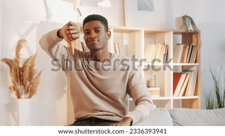 Disapproval sign. Disagree gesture. Negative mood. Upset frustrated man with thumbs down disappointed with apartment in living room interior at home. Royalty-Free Stock Photo #2336393941