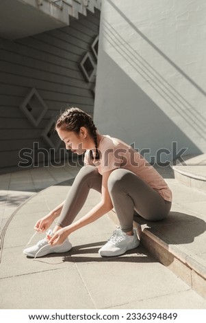 Young Asian woman tying shoelace on her running shoes. Preparation before jogging exercise. Fitness and sport activity. Healthy exercise concept. Royalty-Free Stock Photo #2336394849