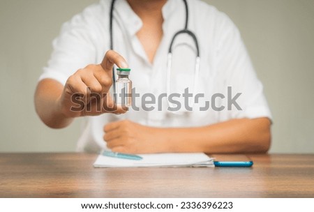 A Physician holds a vaccine bottle while sitting at the table in the hospital. Concept of medical and healthcare