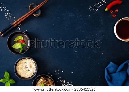 Empty black board with chopsticks, sesame and sou sauce on 