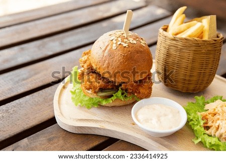 Chicken burger and french fries on a wooden cutting board