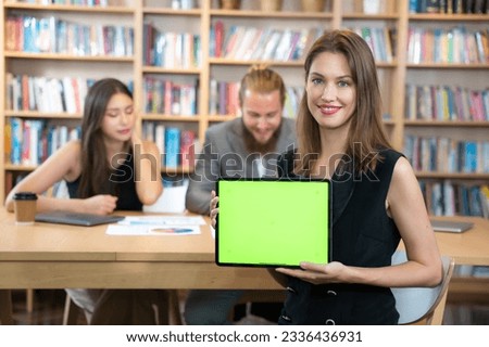 Portrait of business woman show Green screen tablet to camera with smiling. She success with business deals with team.