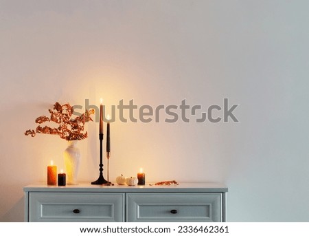 beautiful autumn home decor with burning candles in white interior