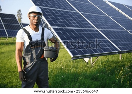 Portrait of african american electrician engineer in safety helmet and uniform installing solar panels