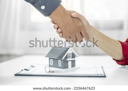 Businessmen and brokers real estate agents shake hands after completing negotiations to buy house insurance and sign contracts. Home insurance concept.