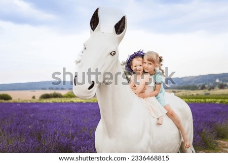 An image of two sisters sitting on a white decorative horse in a lavender field is shown in the picture