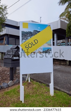 Real estate agency sold sign in front of a house