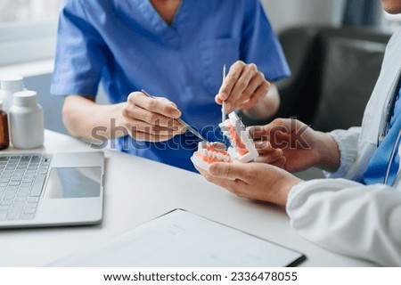 Dentist sitting at table with jaw samples tooth model and working with tablet and laptop in dental office professional dental clinic. medical team doctor working
 Royalty-Free Stock Photo #2336478055