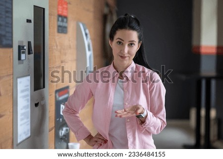 Brunette woman standing near automatic vending machine.