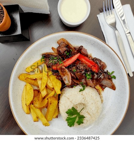 
Peruvian food "lomo saltado": salted meat with tomatoes, onion, fried potatoes and rice. Royalty-Free Stock Photo #2336487425