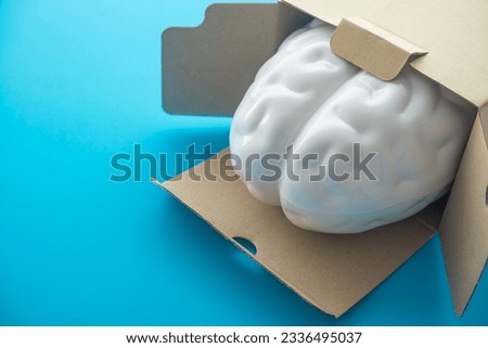 Smart brain is going out of the paper box on blue background copy space. Concept of think outside the box, creative new idea, innovation technology, think different, startup business.