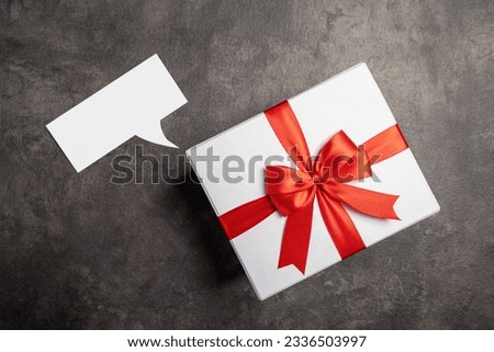 Empty paper with speech symbol and gift box on black background. Empty area for copy space