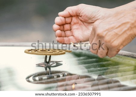A person lighting a mosquito coil. A woman with a lit match in her hand is about to light a coil. Concept for insects, mosquito, insecticides, repellent, bug spray and insect repellent. Royalty-Free Stock Photo #2336507991