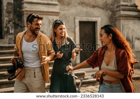 Tourists in the city, the man holding a camera, an Asian woman is pushing a bike, exploring and capturing the city's iconic landmarks in a snapshot-worthy moment. Royalty-Free Stock Photo #2336528143
