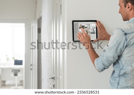 man using tablet panel application for control smart home living. Blonde female touch Wireless device controller for home automation on the wall Royalty-Free Stock Photo #2336528531
