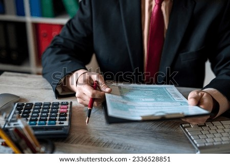 man in a fancy suit fills out a 1040 tax form and uses calculations in the office. tax forms submission of income declaration Royalty-Free Stock Photo #2336528851