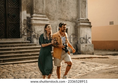 A loving couple strolls along a vibrant street, admiring the colorful buildings and street art. Royalty-Free Stock Photo #2336528911