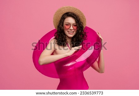 smiling slim happy beautiful woman in stylish swimwear wearing sunglasses and straw hat posing on pink background isolated summer style vacation with inflatable rubber ring