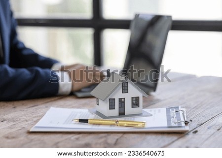 Real estate broker agent presenting and consult to customer to decision making sign insurance form agreement, buy and sell home model, concerning mortgage loan offer for and house insurance
