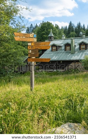 sign for hikers in forest next to old wooden house