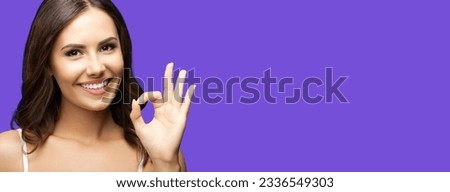 Photo of woman showing ok okay hand sign or zero gesture, isolated on violet purple color background. Portrait of happy smiling gesturing brunette girl at studio. Wide horizontal banner composition.