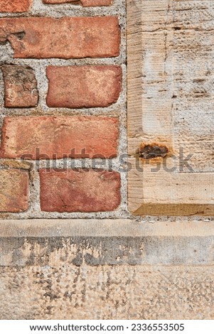 Tan concrete blocks with rough texture on wall with red bricks background asset