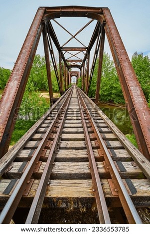 Distant person walking along train tracks on iron truss railroad bridge over Kokosing River