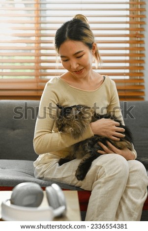 Shot of beautiful young woman playing with her fluffy cat on couch. Human, domestic pet and lifestyle concept Royalty-Free Stock Photo #2336554381
